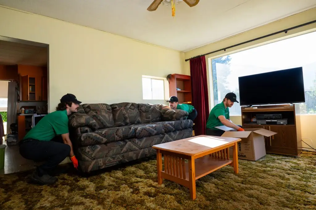Two Fraser Valley Junk Solutions team members lifting a couch while another loads up a box of items