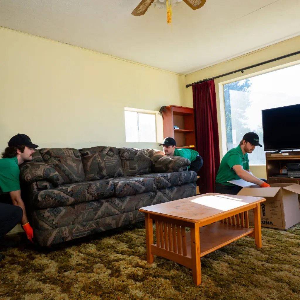 Two Fraser Valley Junk Solutions employees in the process of removing furniture while another employee loads up a box full of items to be donated.
