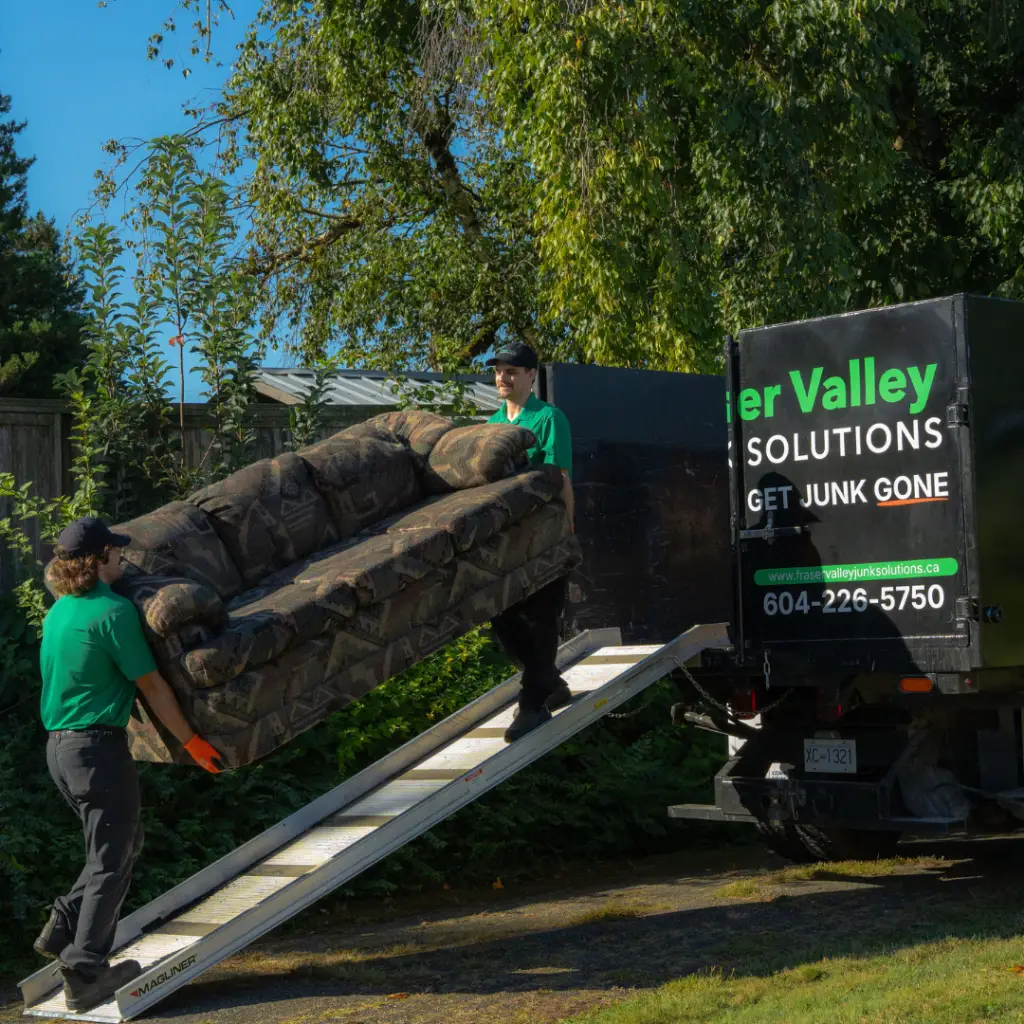 Two Fraser Valley Junk Solutions employees loading up a three seater couch into a FVJS truck for disposal in Chilliwack.